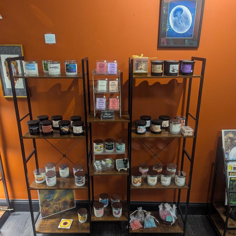 Shelves of handmade candles and gifts with original artwork on the wall