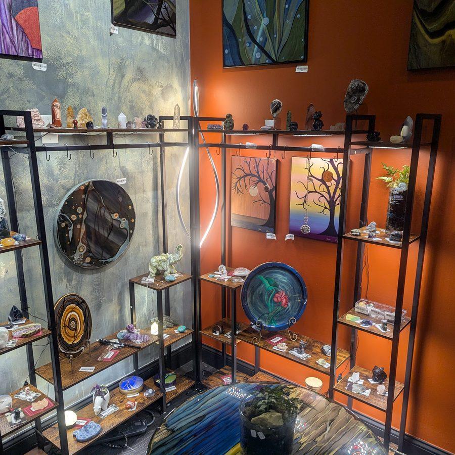 Crystals, gems, and handmade art pieces displayed on black metal shelving