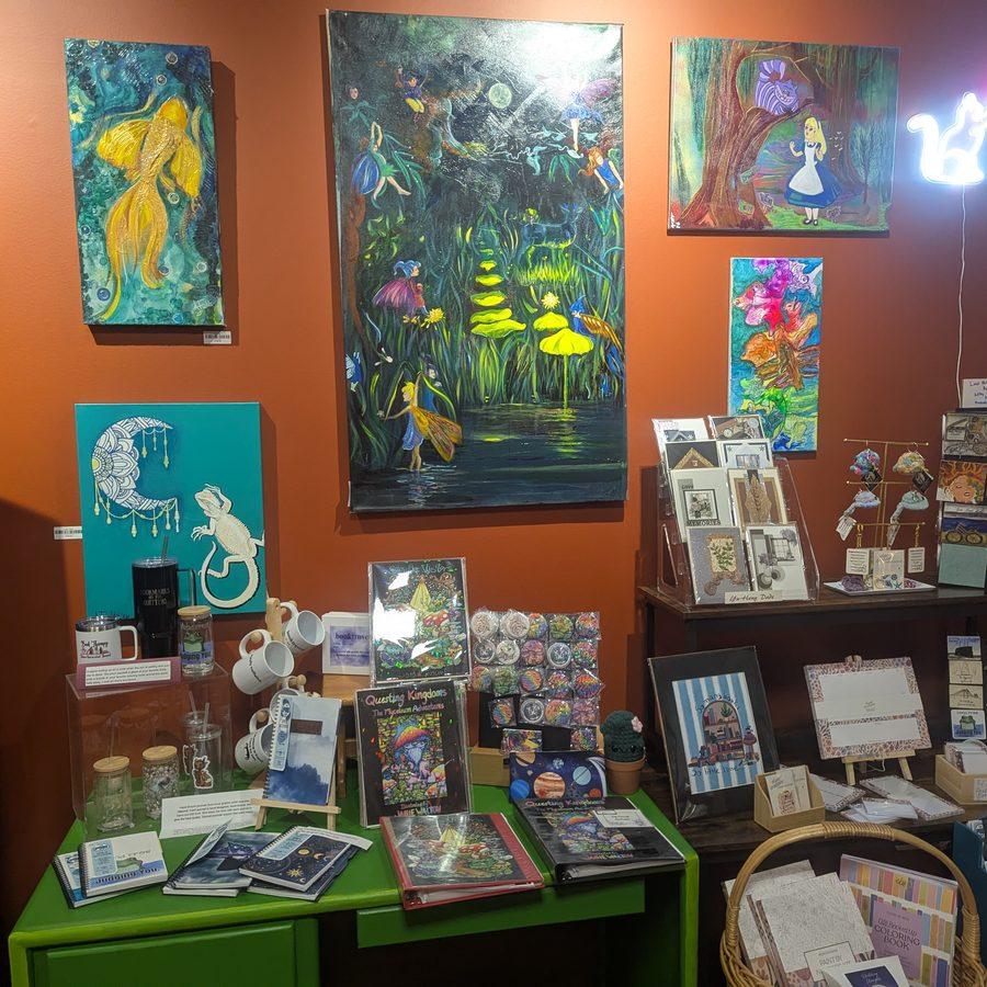 Colorful fairy tale and fantasy paintings displayed above a curated gift table